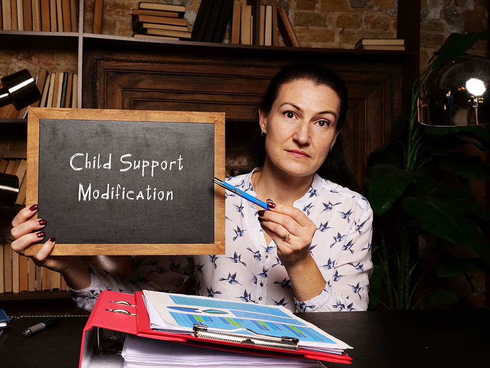 image of woman holding a chalkboard with Child Support Modification written in chalk. Child Support Modifications - Ryan Family Law